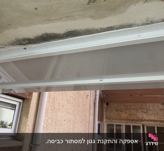 גגון אלומיניום מותקן על קיר חיצוני של מבנה מגורים